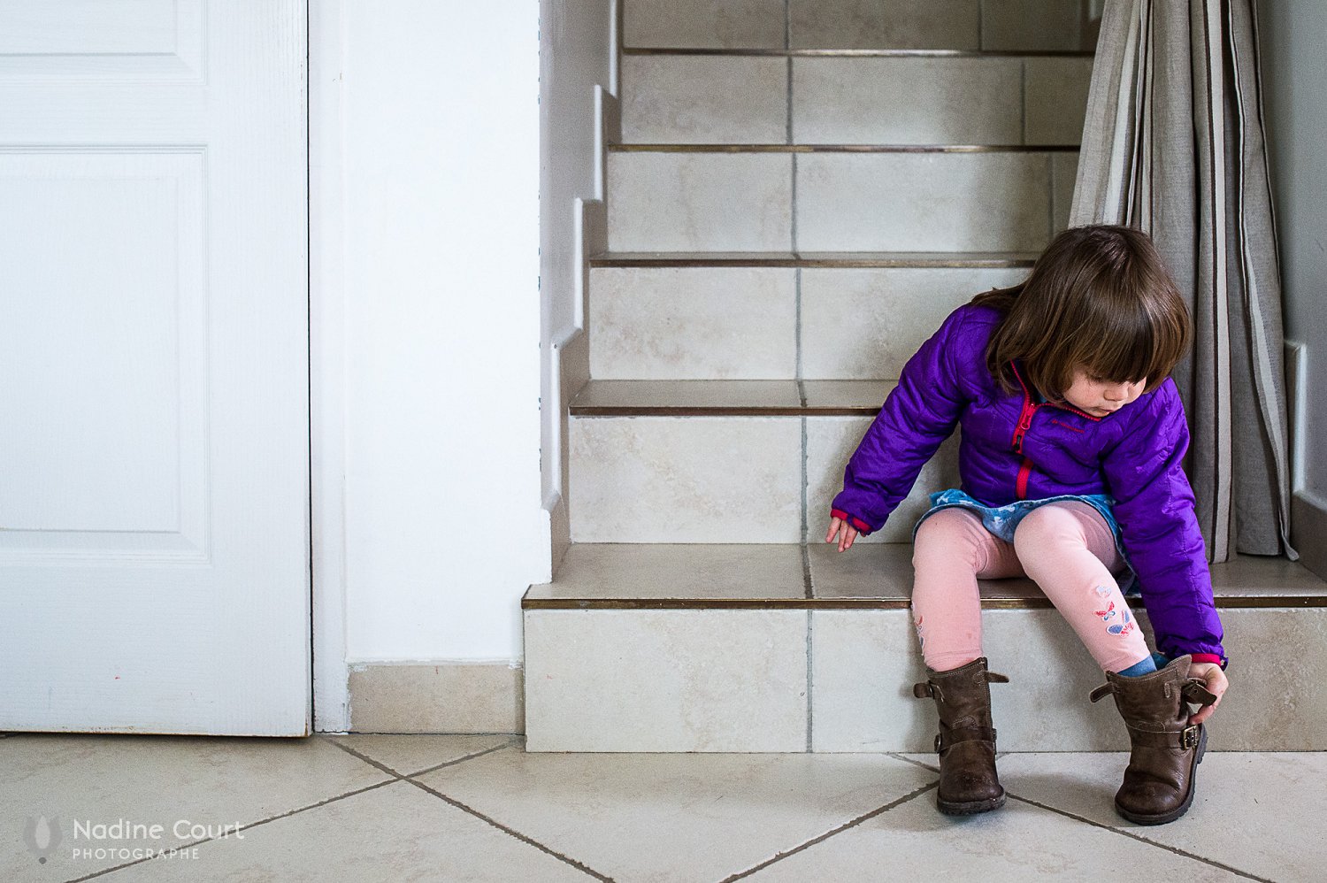 La petite fille enlève ses chaussures en entrant dans la maison