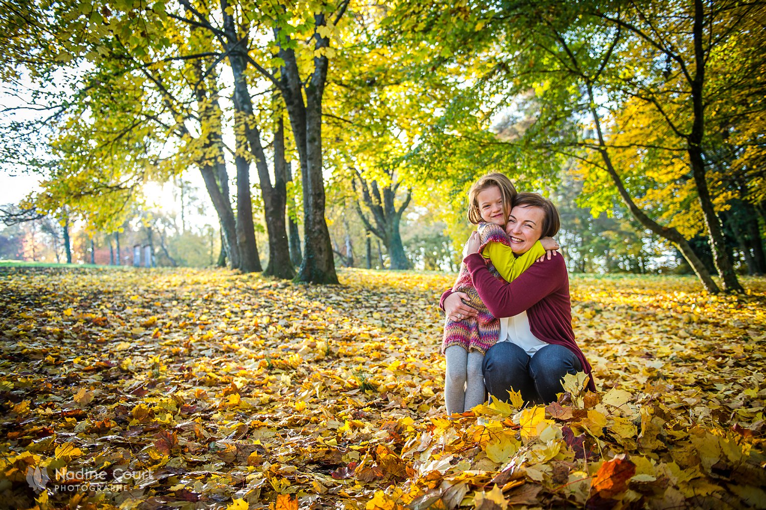 Photo d'une mère et sa fille dans un tas de feuille en automne